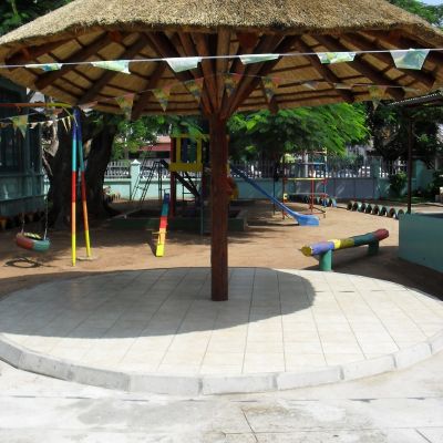 Construcción de una palhota en el patio del orfanato público «1º de Maio» de Maputo,  que permite a las niñas y niños protegerse del sol o la lluvia mientras comparten actividades en grupo.