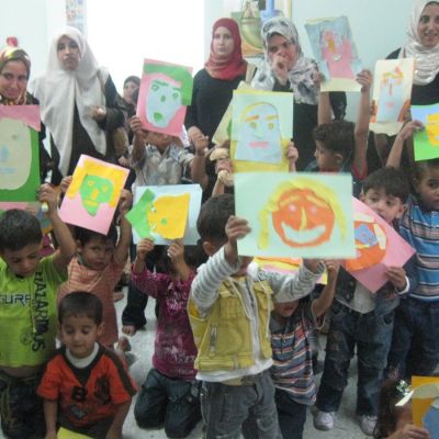 Niños y niñas palestinos/as con las obras realizadas durante sesiones de arte-terapia.