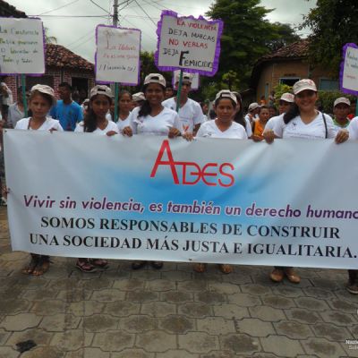 Jóvenes manifestándose en contra de la violencia de género con cartel del proyecto.